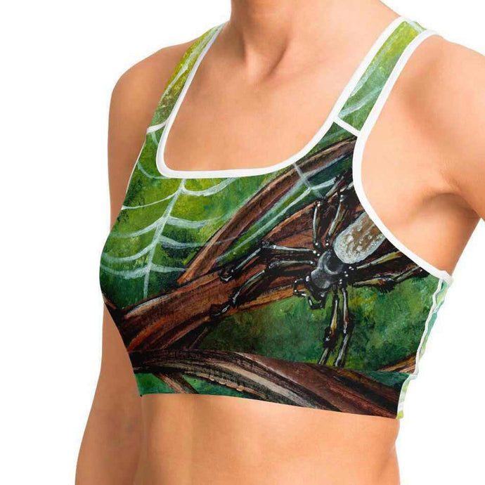 A woman wearing sports bra printed with an illustration of an orb weaver spider in front of its spider web.