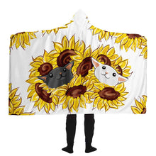 Load image into Gallery viewer, a man wears a white microfiber fleece hooded blanket, printed with sunflower art, with a black cat and white cat peeking out from the flowers
