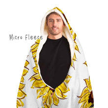 Load image into Gallery viewer, a man wears a white microfiber fleece hooded blanket, lined with micro fleece, printed with sunflower art, with a black cat and white cat peeking out from the flowers
