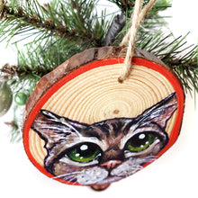 Load image into Gallery viewer, A Christmas wood ornament, features art of the face of a tabby cat with green eyes, and a red border.
