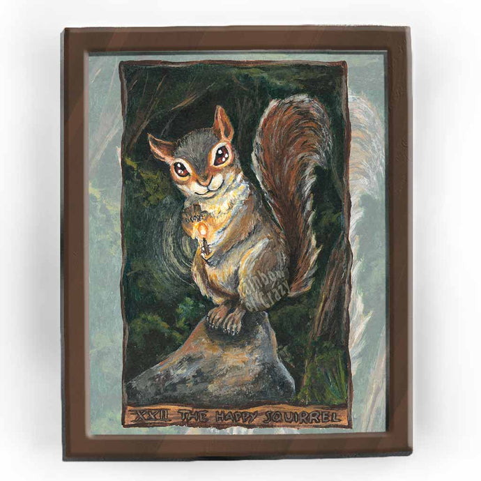 An art print of the happy squirrel tarot card, from the animism tarot: a mischievous looking squirrel sits on a rock in the forest, a lit match in hand.