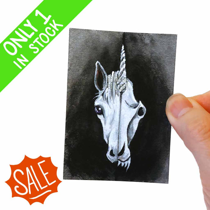 ACEO art print features a split image of a unicorn's face on on the left side, and its slightly scary, stylized unicorn skull on the other.