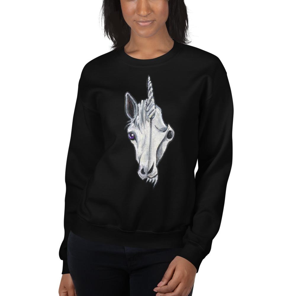 A woman is wearing a unisex sweatshirt in the colour black, which is printed with a split image: the left side features the face of a unicorn, and the right side features an evil looking skull