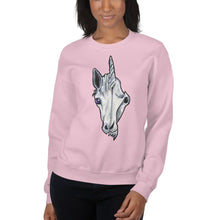 Load image into Gallery viewer, A woman is wearing a unisex sweatshirt in the colour light pink, which is printed with a split graphic: the left side features the face of a unicorn, and the right side features an evil looking skull

