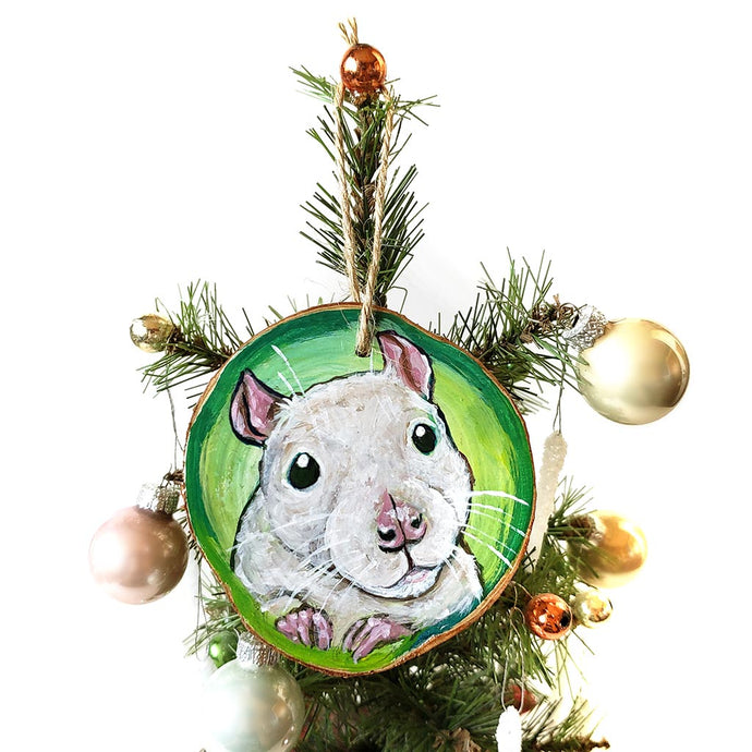 A Christmas wood ornament, hand painted with art of a white fancy rat, in front of a green background