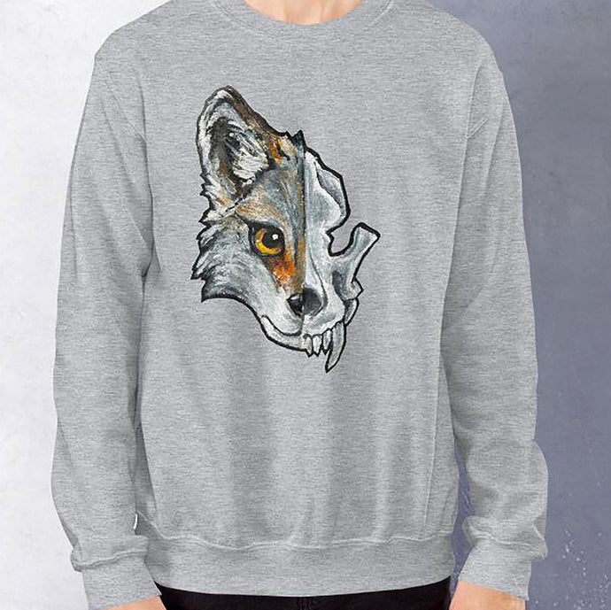 A man wears a unisex sweatshirt in the colour sport grey, printed with a graphic of a split image: the left side features a wolf's face, and the right side features an evil looking wolf skull.