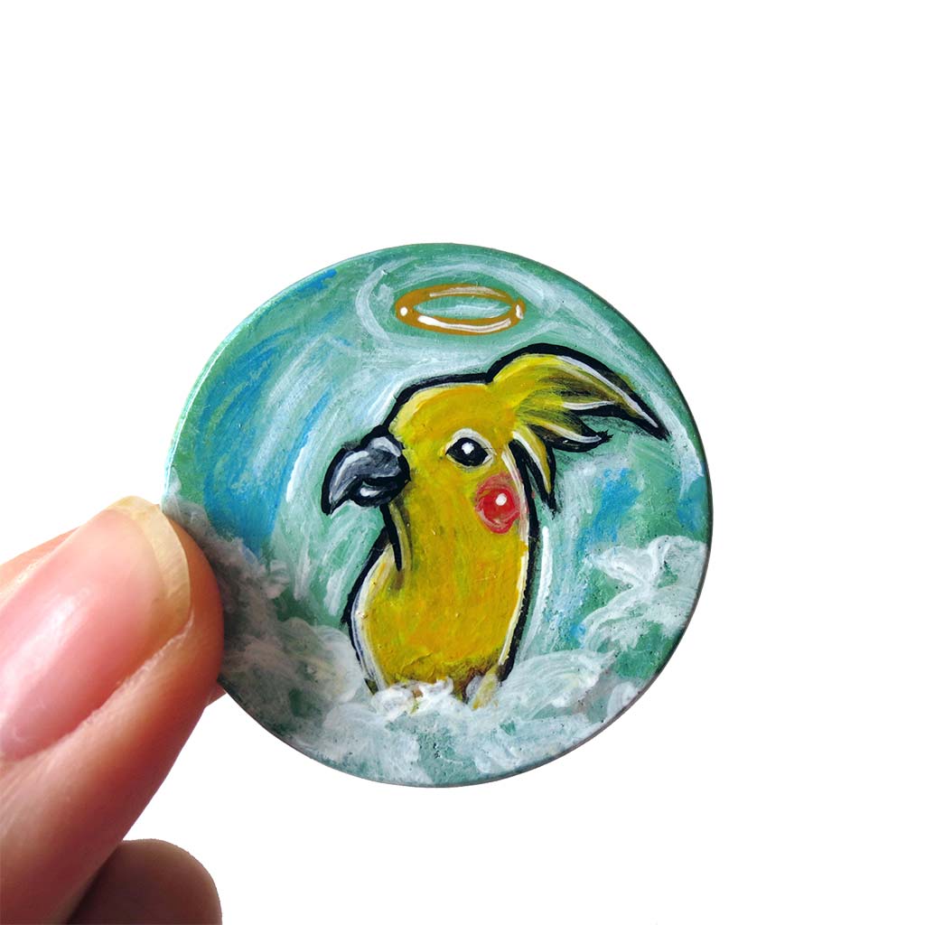 art of a yellow cockatiel as an angel in the clouds, painted on a small wood disc, available as a keepsake or necklace