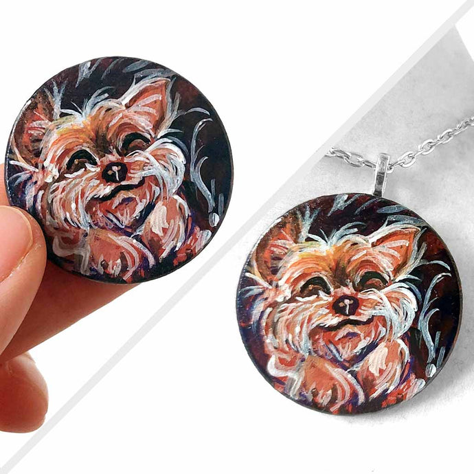 a small wood circle, hand painted with a sleeping, smiling, yorkshire terrier, available as a keepsake or pendant necklace
